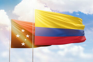 Sunny blue sky and flags of colombia and papua new guinea