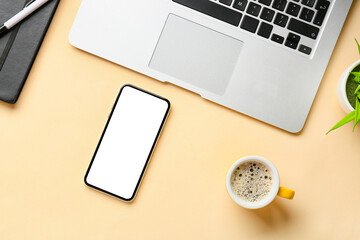 Mobile phone, laptop and cup of coffee on color background