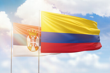 Sunny blue sky and flags of colombia and serbia