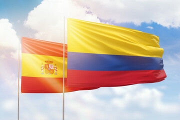 Sunny blue sky and flags of colombia and spain