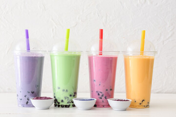 Plastic cups of different tasty bubble tea on table