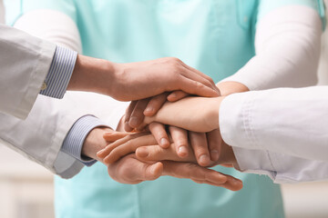 Group of doctors putting hands together in clinic, closeup