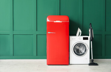 Modern household appliances near green wall in room