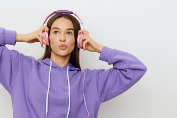 a sweet, beautiful, pleasant woman stands in purple clothes on a white background and puts on headphones