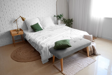Interior of light bedroom with soft bench and houseplants