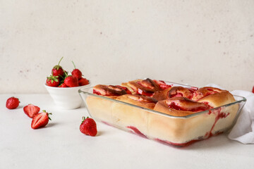 Baking dish with strawberry cinnamon rolls on white background