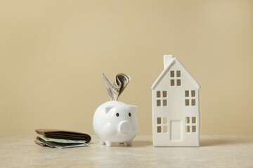 Home budget planning. Cost of living. Inflation concept. Concept of saving money for buying new house. Piggy bank, wallet with dollar banknotes and model of house.  - obrazy, fototapety, plakaty