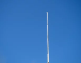 Foto op Canvas Empty white flagpole against the blue sky. Lowered flag. © Aleksandr