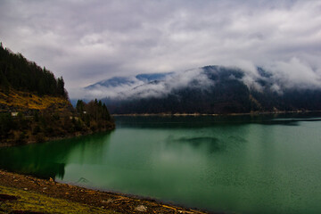 Grüner See in den Bergen mit Nebel 