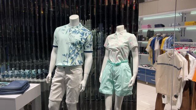 Male and female mannequins without heads stand in the window of a clothing store dressed in shorts and t-shirts. The inscription on the T-shirt: Save the nature!