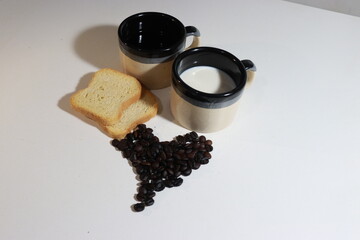 Decoração com grãos de café em formato de coração, torradas e xicaras de café e leite