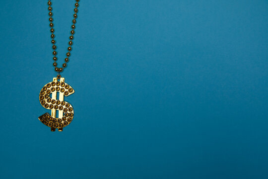 goldkette aus plastik mit dollarzeichen vor einem blauen hintergrund - fotobox requisite um mit der halskette einen erfolgreichen menschen spa&szlig;ig darzustellen