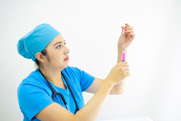 Beautiful woman doctor wearing uniform and blue surgical cap, stethoscope, preparing injection on white background