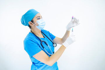 Beautiful woman doctor wearing mask face, uniform and blue surgical cap, stethoscope and latex gloves, preparing injection on white background