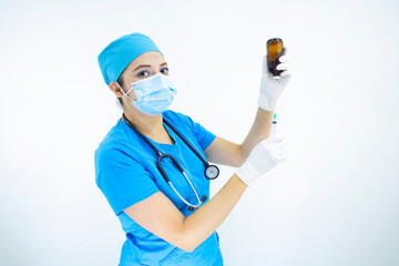 Beautiful woman doctor wearing mask face, uniform and blue surgical cap, stethoscope and latex gloves, preparing injection on white background