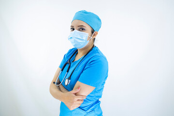 
Beautiful female doctor wearing uniform and blue surgical cap, face mask and latex gloves. professional woman on white background