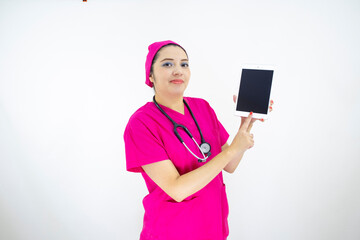 beautiful woman medical assistant, wearing pink uniform and pink surgical cap, stethoscope, using the tablet to display results on white background