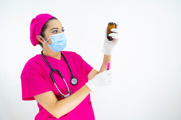 beautiful woman medical assistant wearing face mask, uniform and pink surgical cap, stethoscope and latex gloves, preparing injection on white background