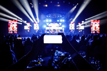 Smartphone in a hands on a music concert show, blank white screen mockup.