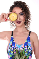 Portrait of a beautiful exsotic fashion girl brunette in the studio in a swimsuit, and a woth fruity with a pineapple