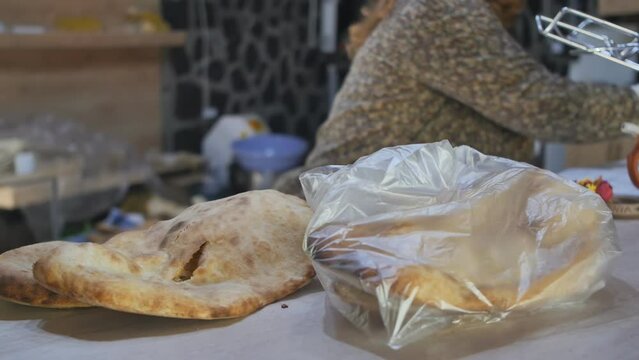 the female hands of the seller put the baked national matnakash in packages and give it to the buyer. Bread products of the peoples of Armenia, Azerbaijan and Turkey.
