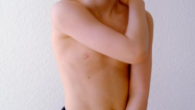 part of thin boy, child 8 years old with a bare torso is standing in front, good posture, prevention of scoliosis in childhood, concept of hearing health, happy childhood, anorexia