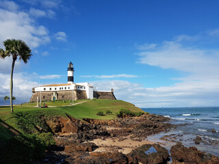 Fototapeta na wymiar Lighthouse built over old stone fort on Salvador beach in Bahia