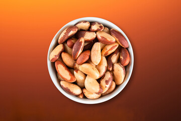 Brazil nuts in bowl top view with colored gradient background