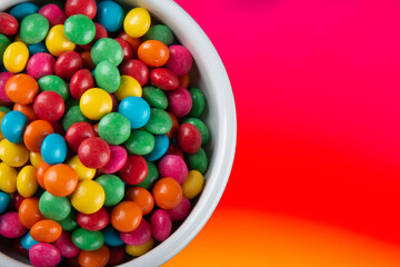 Sweet colored confetti in white bowl top view.