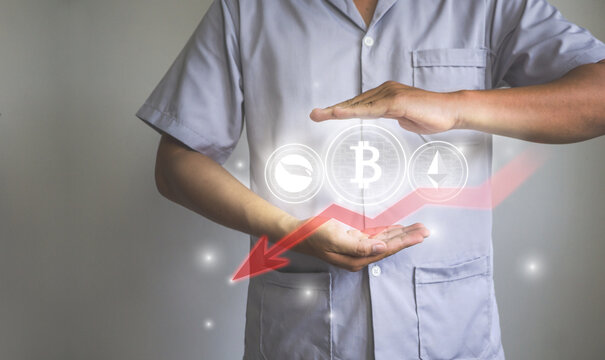 Human hands holding crypto currency coins with decrease red arrow icon, Bitcoin crypto currency concept.