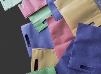 collection of tote bags in pastel colors isolated on a dark gray background. made of polypropylene....