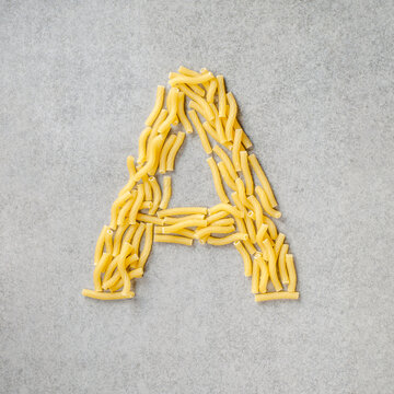Alphabet Pasta Creativity - Letter A - Closeup of Italian ABC raw uncooked vermicelli, macaroni, noodle, pastry, pasta on the isolated bowl