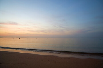 Calm sea shore with crushing waves on sandy beach at sunrise