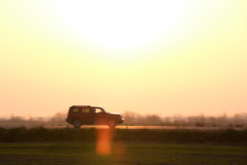 Fototapeta premium SUV car driving fast on intercity road at sunset. Highway traffic in evening