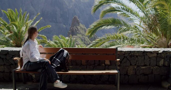 Masca Gorge and village, Tenerife. Beautiful young woman sitting on a bench and enjoying the view