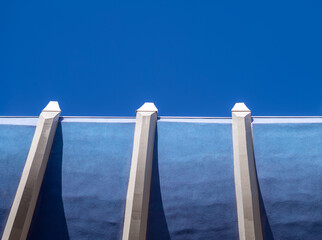 Fototapeta na wymiar Blue and White Open Air Building Wall and Ceiling with Blue Sky Above.