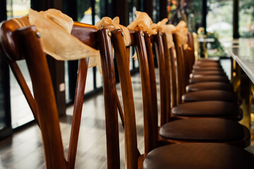 Set of brown chairs and wooden dining table in luxury style restaurant. Interior decoration furniture object. Close-up and partial focus at chair's part.