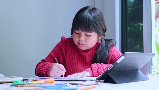 Asian girl sitting at home coloring pictures.