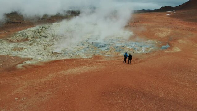 Two Tourists Looking at Steaming Fumaroles in Hverir Geothermal Area