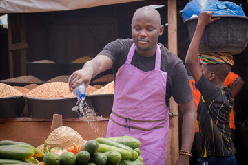 An African Nigerian male trader, seller, business man or shop owner with an apron on his body,...