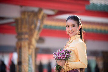 Portrait of an Asian woman in traditional Thai dress in natural light and a Thai temple