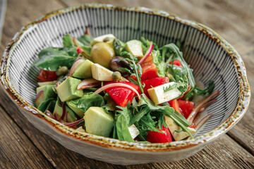 Bowl of fresh gourmet avocado salad on wooden background