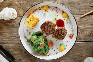 Portion of grilled fillet mignon steak with corn on wooden background