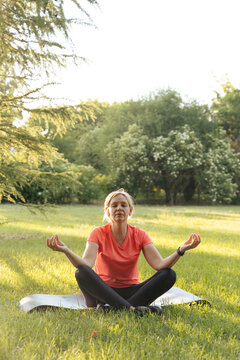 Mature Woman Meditate Outdoors In A Park On Sunset. Mindful Mature Sport Activity 