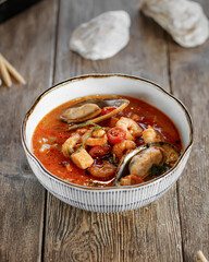 Top view on bowl of tom yam soup on wooden background