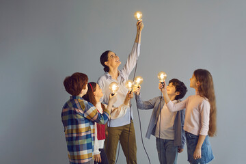 Creative junior kids generating smart genius idea. Smiling enthusiastic teacher as guiding light...