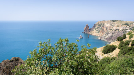 Obraz premium Seascape, rocks and greenery, the southern sea. A ship on the water. Recreation concept on the sea. Front view.