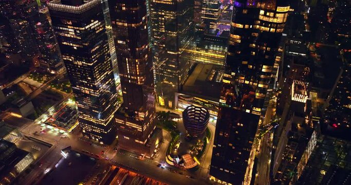 Broad light streets among the skyscrapers of New York. Drone rising along the shining glamorous buildings.