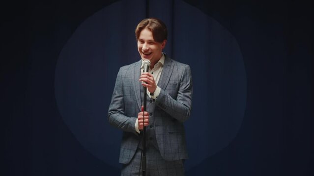 StandUp cafe, comedy concert. Man telling jokes on stage. Male comedian speaks with audience using microphone, humorous monologue. Mentor coach training. Public speaking masterclass. 