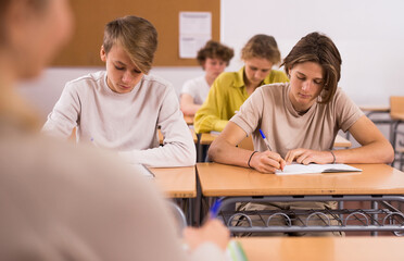 Portrait of teenage school girl and boy sitting together in classroom during lesson in secondary...